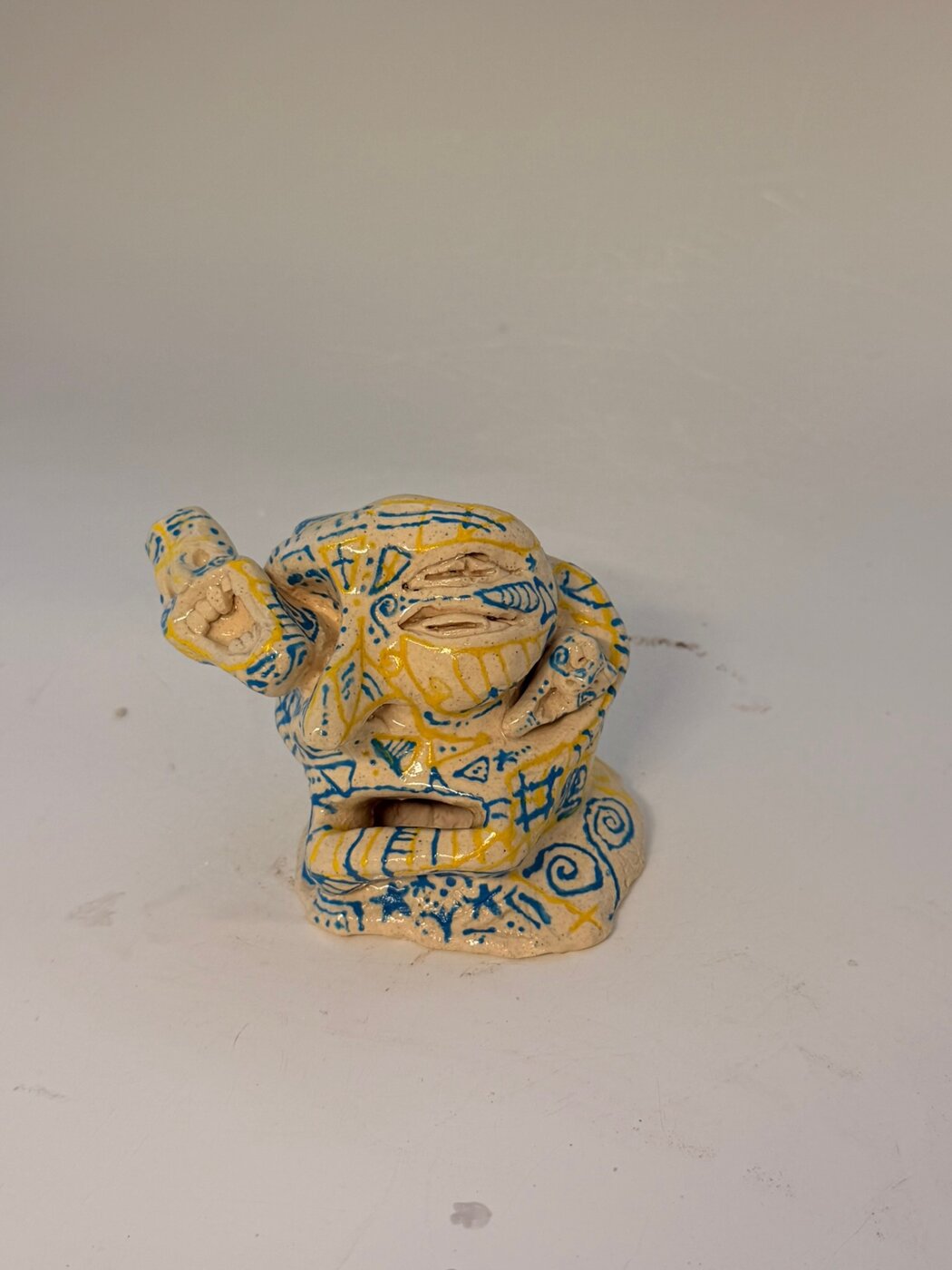 Glazed clay figure decorated with blue and yellow patterned line work