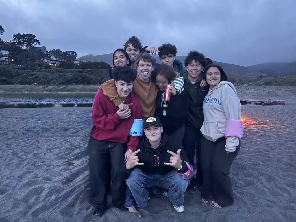 Harris Albee with friends gathered around a beach bonfire at dusk